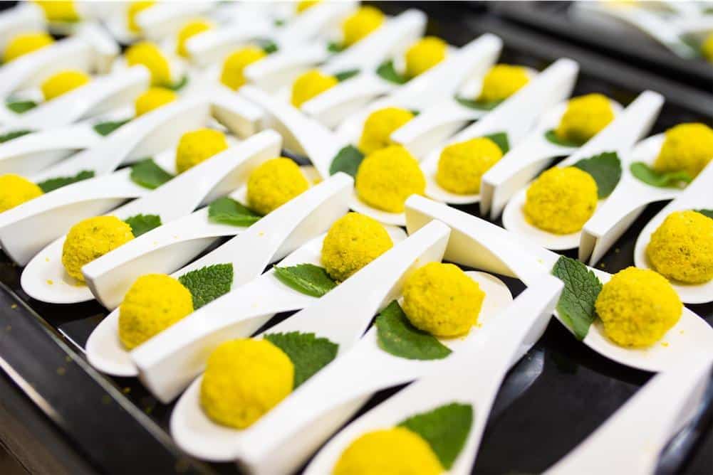 Variedad de canapés y bocados creativos servidos durante un cóctel nupcial. Composición visual armónica con ingredientes frescos y decoración sofisticada.